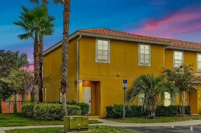a yellow house with palm trees in front of it at Encantada Resort Vacation Townhomes by IDILIQ in Kissimmee