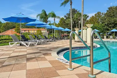a pool with chairs and umbrellas at a resort at Encantada Resort Vacation Townhomes by IDILIQ in Kissimmee