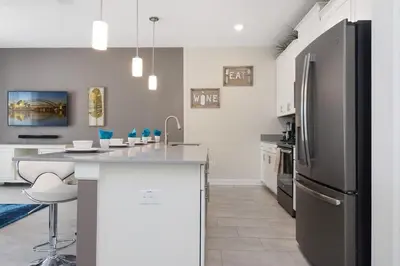 a kitchen with a stainless steel refrigerator and a counter at Four Bedrooms with Screen PoolStoreyLake 4910 in Kissimmee