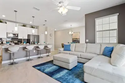 a living room with a white couch and a kitchen at Four Bedrooms with Screen PoolStoreyLake 4910 in Kissimmee