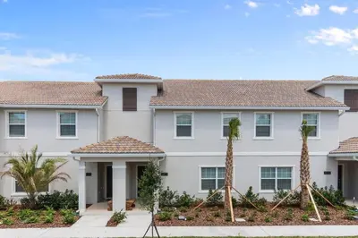 a large white house with palm trees in front of it at Four Bedrooms with Screen PoolStoreyLake 4910 in Kissimmee