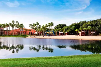 a pond in a park with palm trees and a playground at Walt Disney World Swan in Orlando
