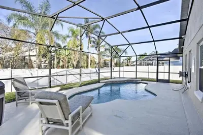a swimming pool in a glass house with two chairs at Mickeys Landing - Luxurious 4BR with 2 Master Suites, Privacy Fenced Pool & Hot Tub BBQ Game RM 2 miles to Disney! in Orlando