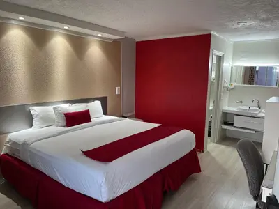 a bedroom with a large bed with a red wall at Travelodge by Wyndham Orlando at Heart of International Drive in Orlando