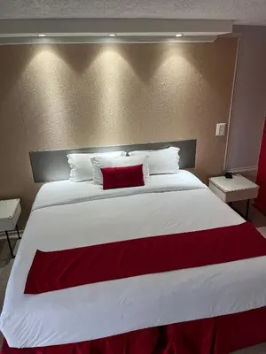 a bedroom with a large white bed with a red blanket at Travelodge by Wyndham Orlando at Heart of International Drive in Orlando