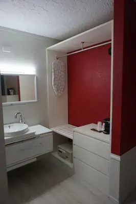 a bathroom with a sink and a red wall at Travelodge by Wyndham Orlando at Heart of International Drive in Orlando