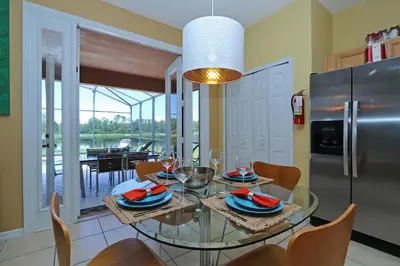 a dining room with a glass table and a refrigerator at Aquamarine Hideaway in Kissimmee