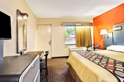 a small hotel room with a bed and a desk at Super 8 by Wyndham Kissimmee/Maingate/Orlando Area in Orlando