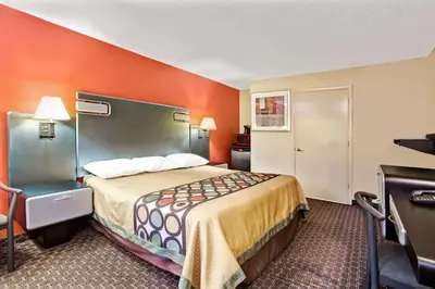 a hotel room with a bed with an orange wall at Super 8 by Wyndham Kissimmee/Maingate/Orlando Area in Orlando