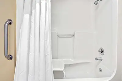 a shower with a white shower curtain in a bathroom at Super 8 by Wyndham Kissimmee/Maingate/Orlando Area in Orlando