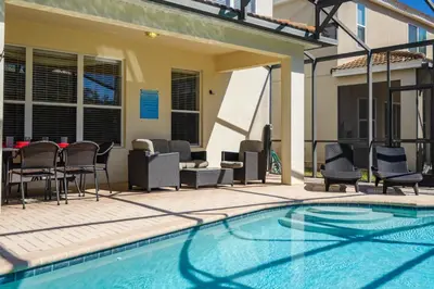 a swimming pool with chairs and a table next to a building at Flagstone Villa in Orlando
