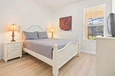 a bedroom with a white bed and a tv at Flagstone Villa in Orlando