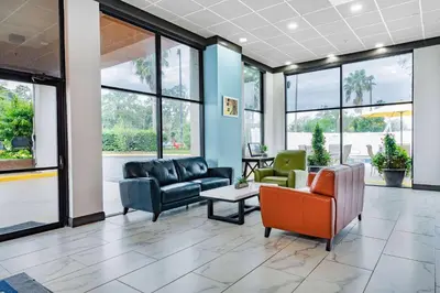 a lobby with couches and chairs and windows at Days Inn by Wyndham N Orlando/Casselberry in Orlando