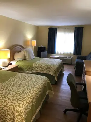 a hotel room with two beds and a chair at Days Inn by Wyndham N Orlando/Casselberry in Orlando