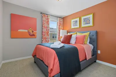 a bedroom with a bed with an orange wall at 4Bd Sleeps 9 w Jacuzzi Close to Disney @ Compass Bay 5113C in Kissimmee