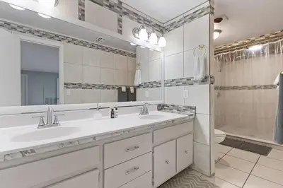 a white bathroom with two sinks and a shower at Spacious Lakefront House with Pool, Hottub, & Boating in Orlando