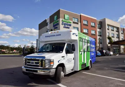 a white and green bus parked in a parking lot at Holiday Inn Express & Suites - Orlando - Southeast by IHG in Orlando