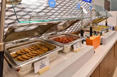 a buffet line with trays of food on a counter at Holiday Inn Express & Suites - Orlando - Southeast by IHG in Orlando