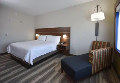 a hotel room with a bed and a chair at Holiday Inn Express & Suites - Orlando - Southeast by IHG in Orlando