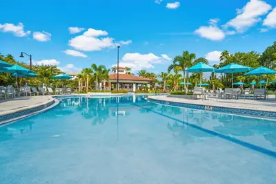 a swimming pool at a resort with blue umbrellas at Cayview Avenue Unit 103 Condo in Orlando