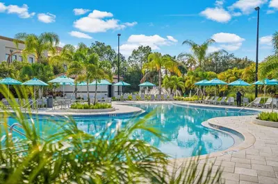 a swimming pool at a resort with blue umbrellas at Shoreway Loop Unit 108 Condo in Orlando