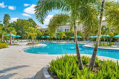 a resort swimming pool with palm trees and umbrellas at Shoreway Loop Unit 407 Condo in Orlando