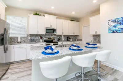 a kitchen with white cabinets and a large island with white chairs at Beautiful Home wPrivate Pool & Spa, near WDW in Kissimmee