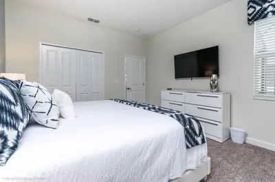 a bedroom with a white bed and a television at Beautiful Home wPrivate Pool & Spa, near WDW in Kissimmee