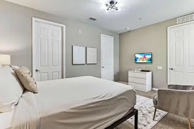a bedroom with a large white bed and a chair at 4804 Cayview Ave #105 in Orlando