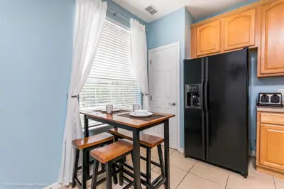 a kitchen with a small table and a black refrigerator at Lovely Townhome at Vista Cay Resort near WDW in Orlando