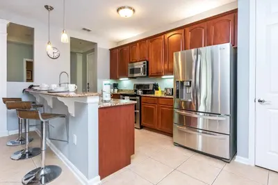 a kitchen with wooden cabinets and a stainless steel refrigerator at Beautiful Condo w Private Balcony Near Universal in Orlando