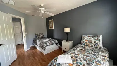 a bedroom with a bed and a chair and a ceiling fan at Your Oasis Awaits! Indulge at Florida Hideaways 4BD Pool Home in Kissimmee