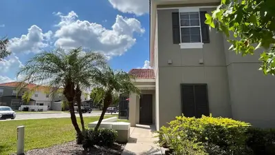 a house with a palm tree in front of it at Your Oasis Awaits! Indulge at Florida Hideaways 4BD Pool Home in Kissimmee