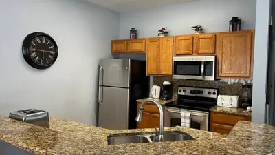 a kitchen with a stainless steel refrigerator and a clock at Your Oasis Awaits! Indulge at Florida Hideaways 4BD Pool Home in Kissimmee