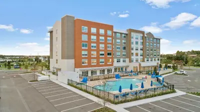 an apartment building with a pool in front of a building at Holiday Inn Express & Suites Orlando- Lake Buena Vista by IHG in Orlando
