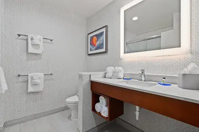 a bathroom with a sink and a toilet and a mirror at Holiday Inn Express & Suites Orlando- Lake Buena Vista by IHG in Orlando