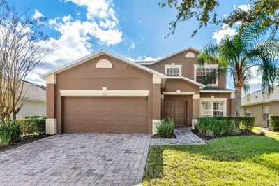 a house with a garage and palm trees at Holiday Villas of Kissimmee in Kissimmee