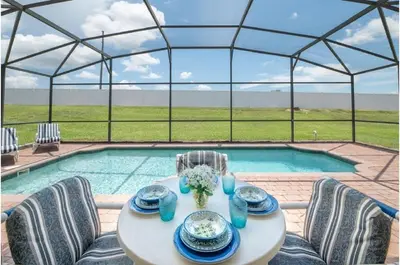a table and chairs in front of a pool at Holiday Villas of Kissimmee in Kissimmee