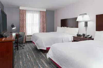 a hotel room with two beds and a desk and a television at Hampton Inn & Suites Orlando Airport at Gateway Village in Orlando