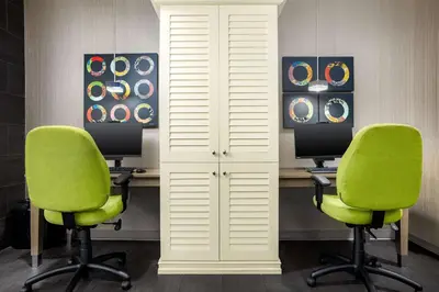two desks with green chairs in a room at Home2 Suites By Hilton Clermont in Clermont