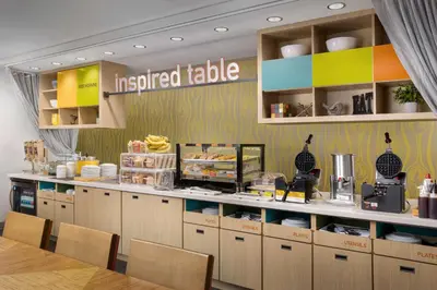 a fast food restaurant with aoked table with chairs at Home2 Suites By Hilton Clermont in Clermont