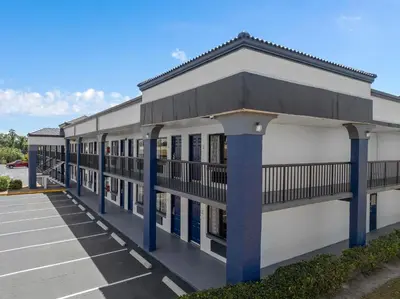 a building with blue columns in a parking lot at Baymont by Wyndham Orlando East in Orlando