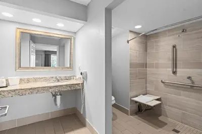 a bathroom with a shower and a toilet and a mirror at Baymont by Wyndham Orlando East in Orlando