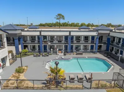 an apartment building with a swimming pool in the courtyard at Baymont by Wyndham Orlando East in Orlando