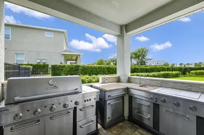 a large outdoor kitchen with a grill and a window at Striking Home With Games, Outdoor Kitchen Near Disney With Waterpark & Resort Access At Encore Resort - 7742Ff in Kissimmee