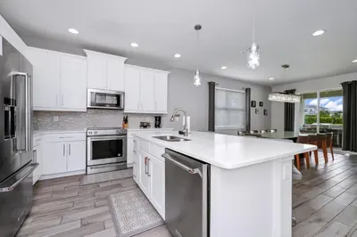 a kitchen with white cabinets and stainless steel appliances at Striking Home With Games, Outdoor Kitchen Near Disney With Waterpark & Resort Access At Encore Resort - 7742Ff in Kissimmee