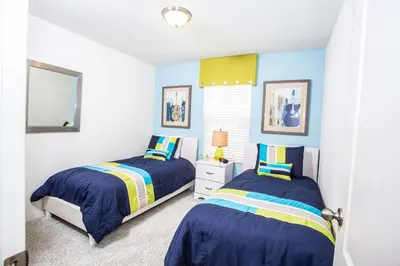 two beds in a bedroom with blue and yellow at Four Bedroom Close to Disney 5149A in Kissimmee