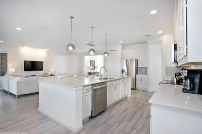 a kitchen with white cabinets and a living room at Sonoma Resort 7 Bedroom Home with Pool 1849 in Kissimmee