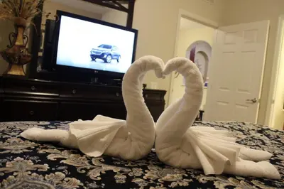 two white swans making a heart on a bed at Viz Cay Apartment 202 in Orlando