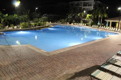 a large swimming pool at night with some chairs at Viz Cay Apartment 202 in Orlando